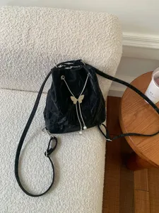 Black bucket backpack with metal butterfly and pearl details, stylish casual daily bag.