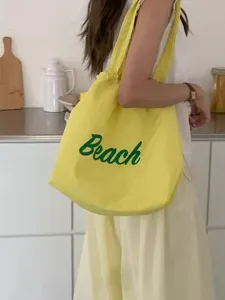 Gele Koreaanse stijl canvas schoudertas met groen Beach letterprint en handig trekkoord.