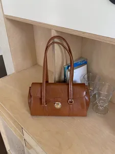 Vintage brown shoulder bag for women, stylish PU leather handbag with metallic clasp.
