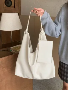 Close-up detail of white hobo shoulder bag with attached small pouch and knot handle design.