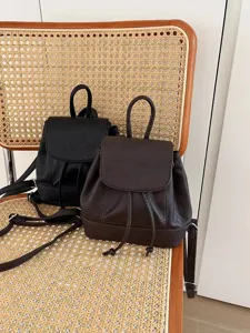 Mini leather backpack detail showing drawstring closure and adjustable straps in black and brown.