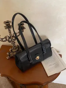 Detailed view of the vintage black leather underarm shoulder bag with metal lock closure.