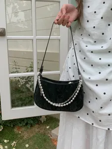 Detailed shot of black shoulder bag featuring pearl metal chains and quilted fabric design.