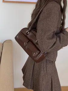 Brown patent leather shoulder bag with dual front pockets, stylish retro underarm handbag for women.