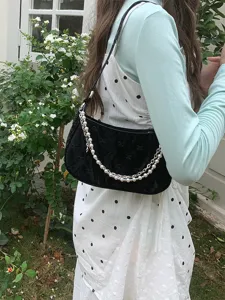Black velvet quilted baguette shoulder bag with elegant pearl and metal chain strap for women.
