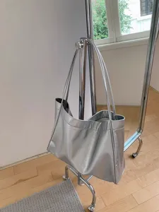 Silver metallic tote bag detail, stylish shoulder bag hanging on a modern chrome rack.