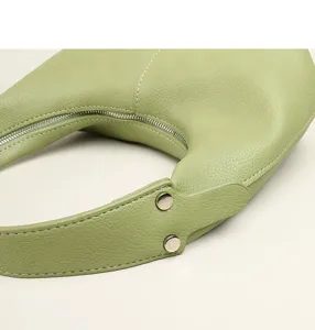 Close-up detail of green pebbled leather hobo shoulder bag with zipper and metal rivet hardware.