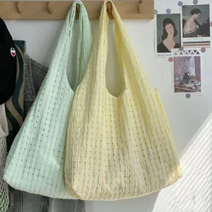 Detail view of stylish checkered tote canvas shoulder bags in mint green and yellow colors.