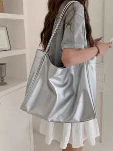 Detail shot of stylish silver metallic tote bag worn on shoulder in minimalist interior.