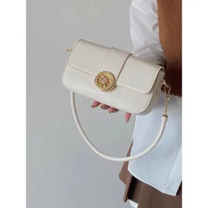 Chic white underarm shoulder bag detail with vintage gold floral buckle and chain strap.