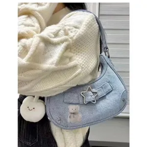 Nahaufnahme der hellblauen Jeans-Umhängetasche mit Sternschnalle und süßer Bären-Stickerei.
