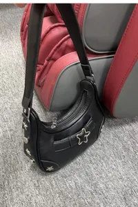 Detailaufnahme einer schwarzen Schultertasche aus Leder mit stylischen Stern-Metalldetails.