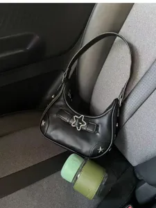 Detailansicht der schwarzen Ledertasche mit Metallsternschnalle und modischem Schultergurt.