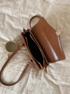 Detail view of brown retro shoulder tote bag featuring metal hardware and open interior section.