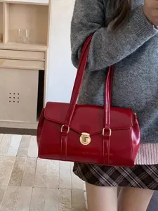 Red patent leather shoulder bag detail, elegant gold metal clasp, stylish feminine accessory.