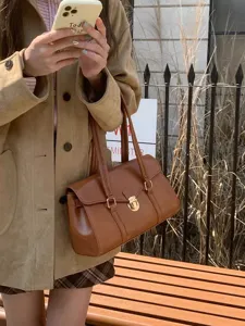 Retro brown leather shoulder bag detail, elegant commuter tote featuring chic metal lock closure.