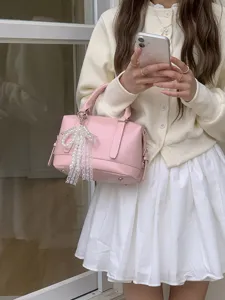 Detail shot of the pink patent leather bowling bag with a pearl lace bow pendant.