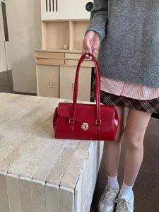 Close-up view of a stylish red patent leather handbag with metal clasp and double top handles.