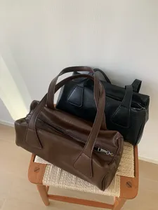 Detail shot of vintage retro barrel shoulder bags in brown and black, casual daily use.