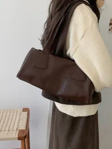 Detailed view of the dark brown leather retro baguette shoulder bag, showcasing fine texture.