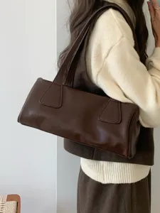 Detail view of stylish retro brown faux leather baguette shoulder bag worn by model.