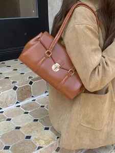 Detail shot of retro brown leather shoulder bag featuring golden metal lock and stylish straps.