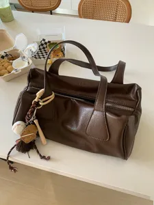 Close-up detail shot of a vintage dark brown faux leather shoulder bag with baseball charm.