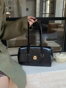 Retro minimalist black gloss leather shoulder underarm bag detail, elegant gold metal lock, chic.