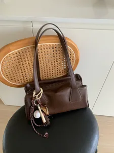 Brown leather baguette shoulder bag with chic sports keychain, perfect vintage daily commuting style.