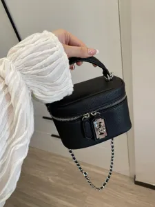 Black pebble leather box bag with metal lock, top handle and silver chain strap for women.