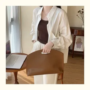 Detailed view of the elegant brown leather 13-inch laptop bag handheld in scene.