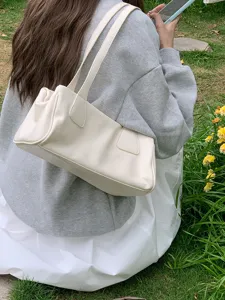 Detailed lifestyle view of the minimalist beige underarm baguette bag, soft leather texture.