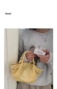 Primo piano di un'elegante borsa a secchiello in pelle verniciata gialla con fiocco.