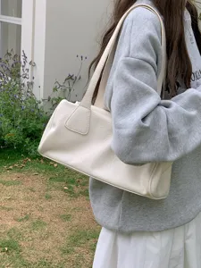 Detail view of the minimalist retro off-white shoulder bag, casual everyday underarm bag style.
