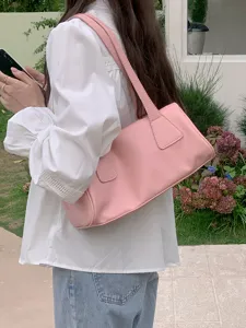 Detail shot of pink shoulder underarm baguette bag, casual everyday style outdoors.