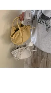 Vista dettagliata di una elegante borsa a secchiello da donna con fiocco e coulisse.