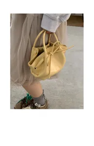 Borsa a secchiello elegante in pelle gialla da donna con fiocco alla moda e manico.