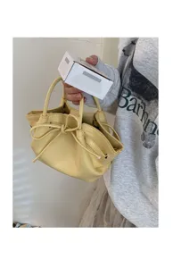 Vista dettagliata della borsa a secchiello gialla da donna con elegante fiocco e manici.