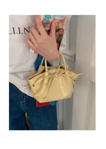 Dettaglio della borsa gialla in vernice con fiocco, mini borsa a secchiello trendy da donna.