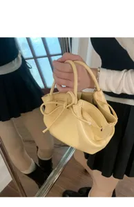 Vista dettagliata di una borsa a secchiello in vernice giallo chiaro con fiocco.