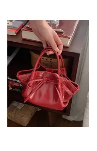 Dettaglio borsa a mano in vernice rossa, grazioso fiocco, elegante mini borsa a secchiello chic.