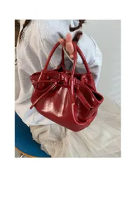 Primo piano dettagliato di una elegante borsa a secchiello rossa lucida con fiocco.