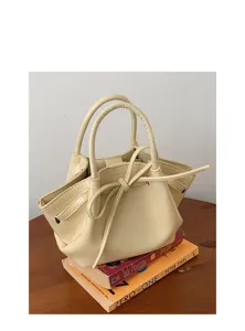 Dettaglio borsa a mano bianca crema con elegante fiocco e doppi manici alla moda.