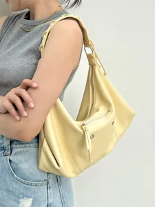 Close-up detail view of the fashionable light yellow hobo shoulder bag worn by model.