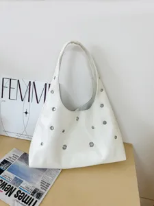 Detail shot of white leather shoulder bag featuring stylish metal eyelets and comfortable strap.