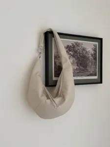 Minimalistische cremefarbene Leder Croissant Schultertasche mit eleganter Halbmondform und Ring.
