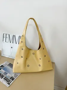 Close-up view of stylish yellow leather shoulder bag featuring chic metallic grommet details.