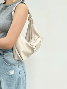 Stylish beige leather shoulder bag detail, vintage motorcycle style underarm bag showcase.