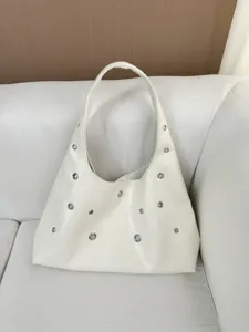 Detailed view of off-white leather shoulder bag with metal grommets and comfortable strap.