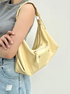 Close-up view of a stylish yellow hobo shoulder bag with zipper pocket and metal detail.